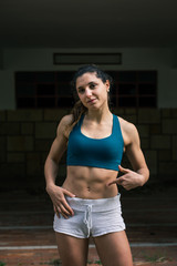 Confident fit athlete pointing her strong abs. Fitness female muscular body.