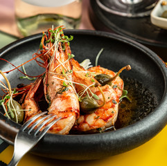 close up of fried prawns garnished with pickles and fresh herbs