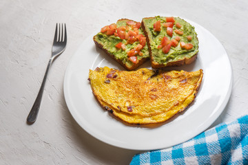 Healthy breakfast with omelette and guacamole toast on white background