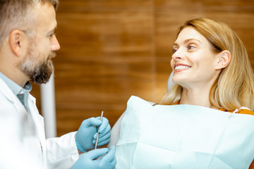 Fototapeta premium Beautiful woman as a patient with senior dentist smiling and feeling trust during a medical consultation at the dental office