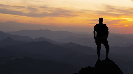 man on top at sunset surrounded by mountains