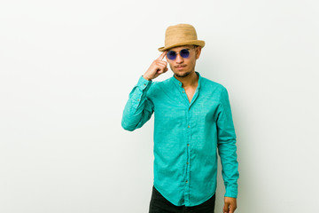 Young hispanic man wearing a summer clothes pointing temple with finger, thinking, focused on a task.