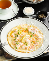 plate of omelette with chicken pieces garnished with cheese and fresh herbs
