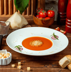 plate of tomato soup garnished with grated parmesan in soup bowl