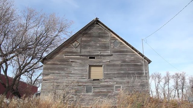 Abandoned old farm house with dry grass surrounding the building.