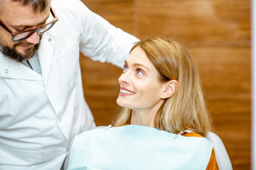 Fototapeta premium Beautiful woman as a patient with senior dentist smiling and feeling trust during a medical consultation at the dental office