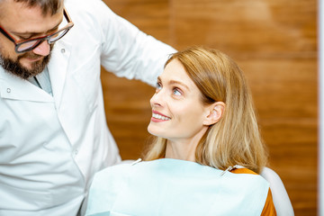 Beautiful woman as a patient with senior dentist smiling and feeling trust during a medical consultation at the dental office