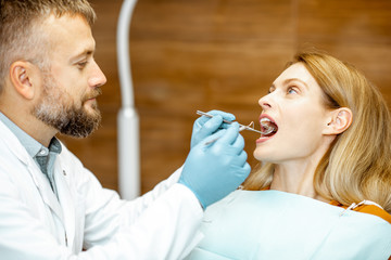 Beautiful woman as a patient during a teeth inspection with a senior experienced dentist at the clinic