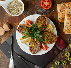 turkish stuffed meatball ichli kofte served with lemon, parsley and tomato