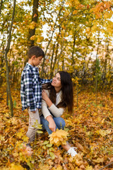 mom and son collecting leaves in autumn park. copy space