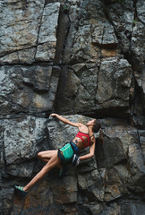 attractive slim muscular young woman rockclimber climbing on tough sport route, resting and...