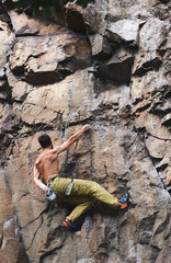 strong muscular man rockclimber climbing on tough sport route, resting and chalking hands.