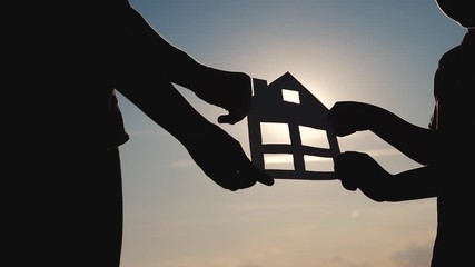happy family construction house teamwork concept. Mom and son holding home a paper house in his hands at sunset silhouette sunlight. life symbol ecology lifestyle video . boy and girl hold paper home