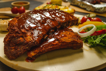 Roasted pork ribs BBQ with baked potato and salad on wooden plate