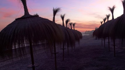 4k sunset gimbal footage tropical beach with tiki umbrellas in marbella, malaga, spain, costa del sol, holiday dream destination
