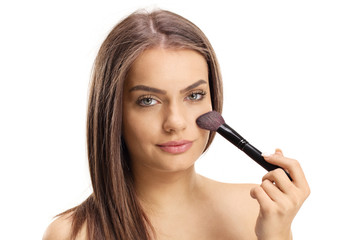 Close up of a beautiful young girl applying make up with a brush
