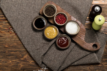 Different spices and sauces with a gray linen tablecloth on a wooden background, studio lighting, top view
