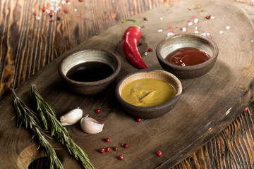 Obraz na płótnie Canvas Various spices, herbs, garlic and sauces on a wooden background, studio lighting, top view