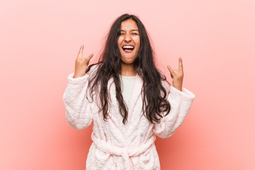 Young indian woman wearing pajama showing rock gesture with fingers