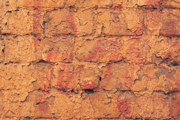 part of a brick wall covered in weathered yellow paint with streaks