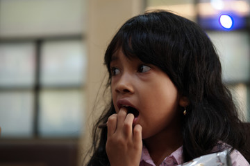 Fototapeta na wymiar Little Asian girl puts her hand on mouth