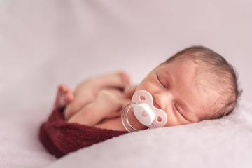 newborn baby with pacifier tucked in a ball of wool. Newborn session concept