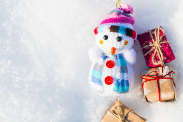 funny toy snowman with gifts in a snowdrift with a copy of space