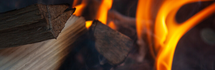 Red-orange flame in a bonfire. Firewood burn in a bonfire close-up. brown firewood and fire in a...