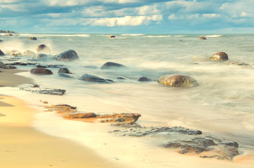 Long Exposure of the Baltic sea landscape. White sand, stones, waves and blue sky. Pakri Peninsula, Harju County, Estonia.
