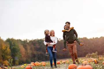 Happy young family in pumpkin patch field