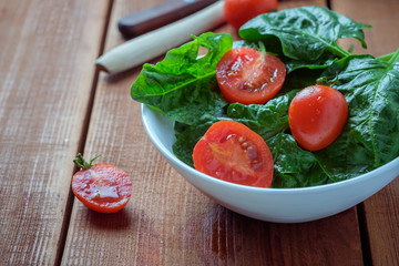 summer salad with tomatoes in white plate on wood table