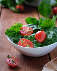 summer salad with tomatoes in white plate on wood table