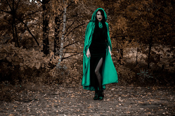 Woman in gothic style wear green carnival cloak, concept of simple Halloween ideas 