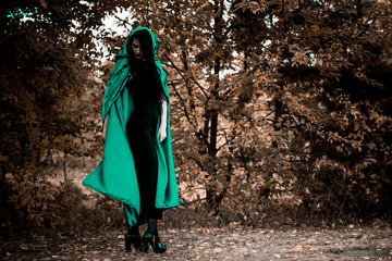 Woman in gothic style wear green carnival cloak, concept of simple Halloween ideas 