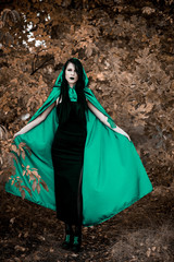 Woman in gothic style wear green carnival cloak, concept of simple Halloween ideas 