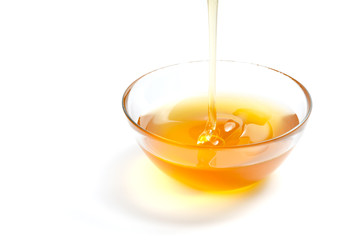 Transparent plate with honey. Honey flows in a plate. White isolated background.