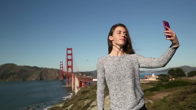 Woman taking selfie with Golden Gate Bridge