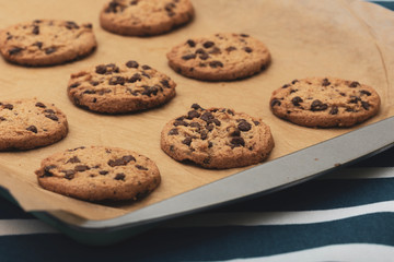 Homemade chocolate cookies on baking paper and baking tray.