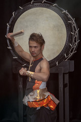 Fototapeta na wymiar Portrait of a Japanese drummer Taiko with drumsticks on the background of a large drum.