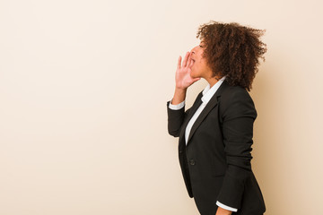 Young business african american woman shouting and holding palm near opened mouth.