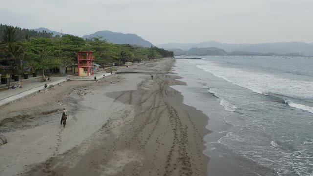 Aerial 4K video of tropical beach with brown sand and waves. Pelabuhan Ratu Beach, Sukabumi, West Java