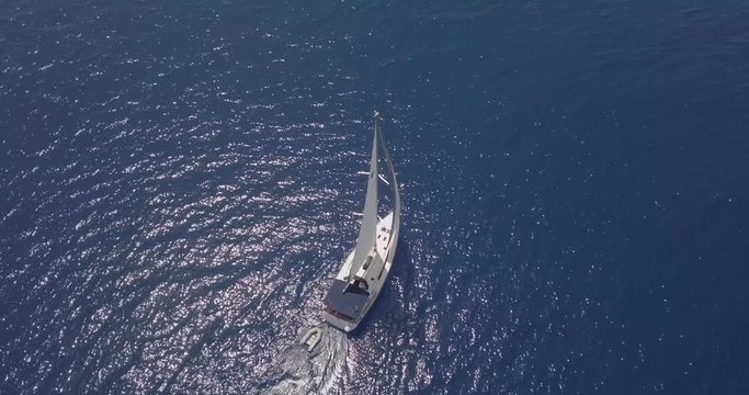 Yacht fully under sail power as it sails through the sparkling ocean