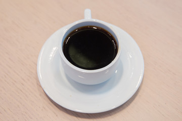 white cup, coffee in white sauce.Cup of hot coffee on table in cafe blur background . coffee beans in white porcelain cup decorated wild herbs .