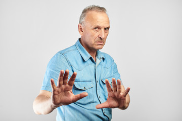Caucasian senior citizen put his hands forward, refuses the offer, does not want to participate in...