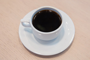 white cup, coffee in white sauce.Cup of hot coffee on table in cafe blur background . coffee beans in white porcelain cup decorated wild herbs .