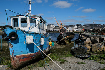Fototapeta na wymiar Blue and white abandoned wooden boat at the edge of the river Corrib in Galway City. Taken on a sunny summer's day.