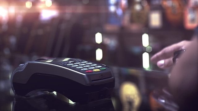 A man using smartwatch to purchase product at the point of sale terminal with near field communication identification technology to complete the transaction