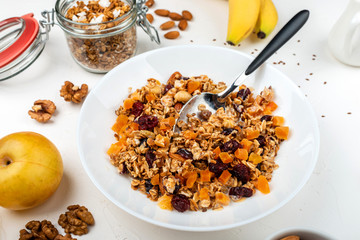 Granola muesli breakfast with with milk, dried apricots, cranberries, almonds and flax seeds in bowl on a white background. Healthy cereal breakfast.
