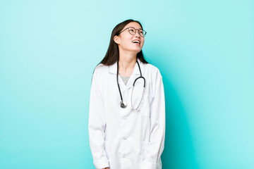 Young chinese doctor woman relaxed and happy laughing, neck stretched showing teeth.