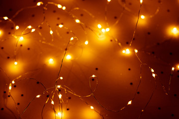 Warm white LED string lights over blur brown background. Modern festive interior decor.